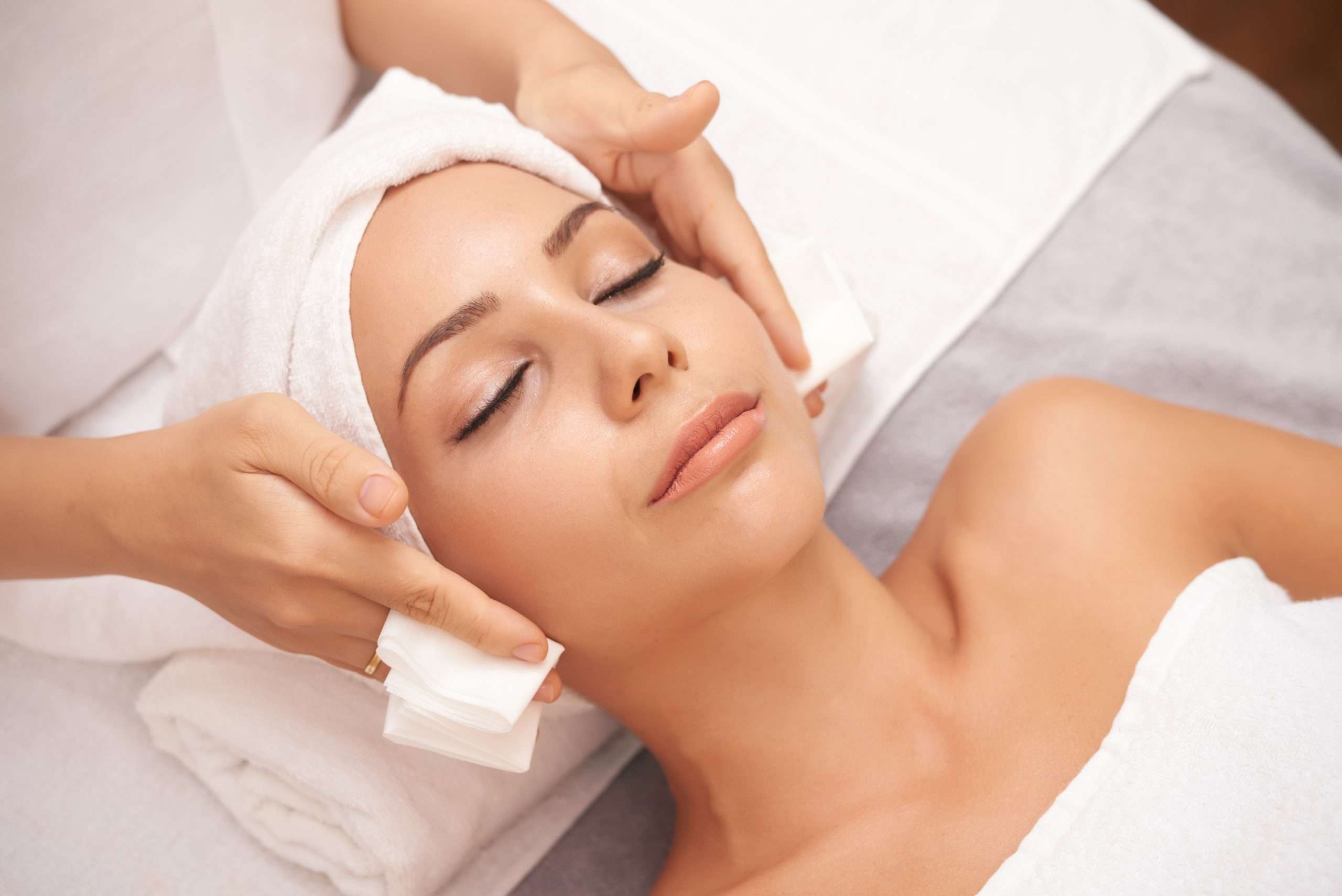 Beautiful young woman with flawless skin enjoying professional facial in beauty salon